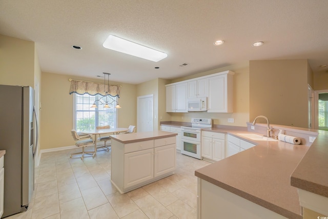 kitchen with a wealth of natural light, white appliances, a sink, and white cabinetry
