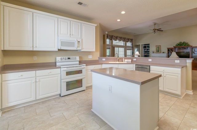 kitchen with visible vents, a sink, white appliances, a peninsula, and ceiling fan