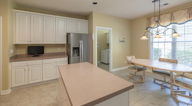 kitchen featuring washer / dryer, visible vents, stainless steel refrigerator with ice dispenser, and white cabinets