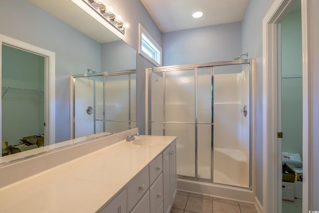 bathroom with a spacious closet, vanity, tile patterned flooring, and a stall shower