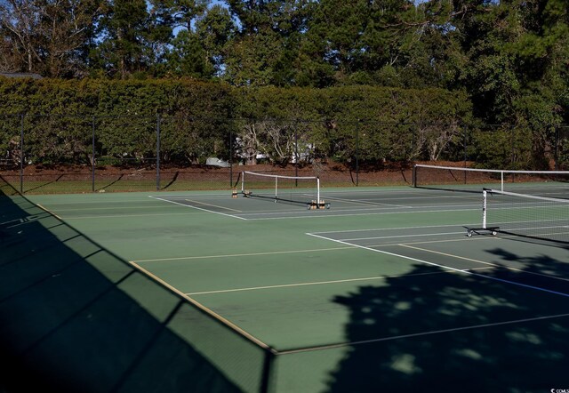 view of tennis court with community basketball court and fence