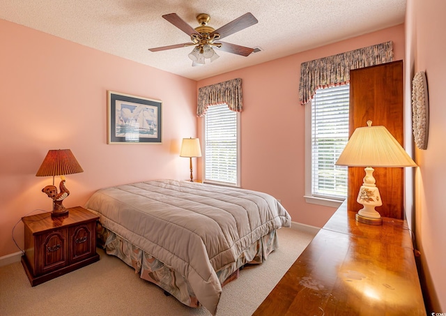 bedroom featuring baseboards, a ceiling fan, wood finished floors, and a textured ceiling