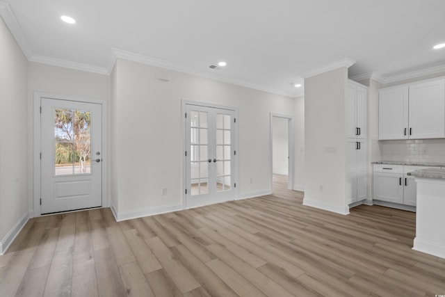 kitchen with light wood-style flooring, white cabinets, tasteful backsplash, baseboards, and ornamental molding