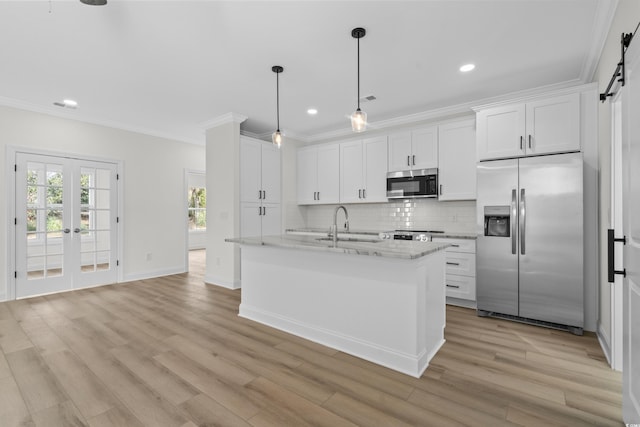 kitchen with appliances with stainless steel finishes, ornamental molding, decorative backsplash, light wood-style floors, and a sink