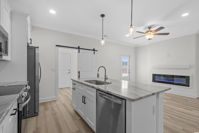 kitchen with a sink, appliances with stainless steel finishes, a barn door, light wood-style floors, and white cabinets