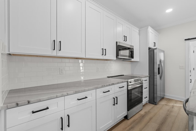 kitchen featuring appliances with stainless steel finishes, light wood-style floors, light stone countertops, white cabinets, and baseboards