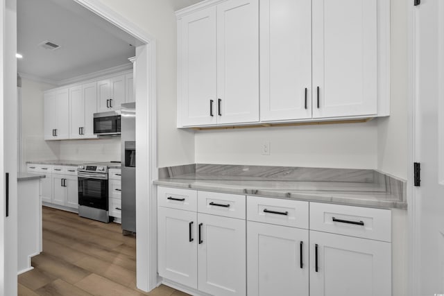 135 Stonewall Cir Unit 7-2, Longs, SC 29568 - kitchen with stainless steel appliances, white cabinetry, light wood-style floors, decorative backsplash, and crown molding