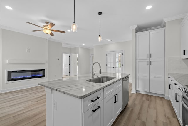 kitchen with a sink, appliances with stainless steel finishes, light wood-style flooring, crown molding, and open floor plan