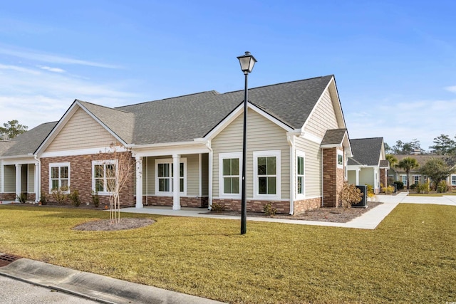 view of front of property with a front lawn, a shingled roof, and stone siding