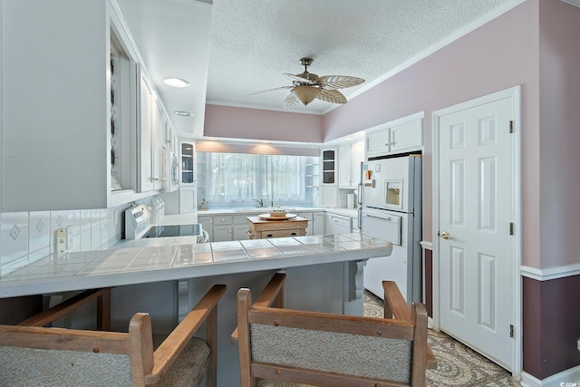 321 Heather Ct, Sunset Beach, NC 28468 - kitchen featuring white appliances, a peninsula, tile countertops, a ceiling fan, and a textured ceiling