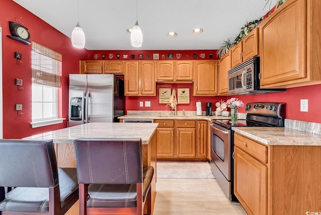 1046 Palisade Cir Unit 1046, Myrtle Beach, SC 29577 - kitchen with stainless steel appliances, a sink, decorative light fixtures, light wood-type flooring, and a kitchen island