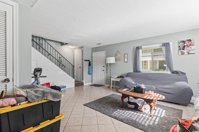 living room featuring baseboards, stairs, a textured ceiling, and light tile patterned floors