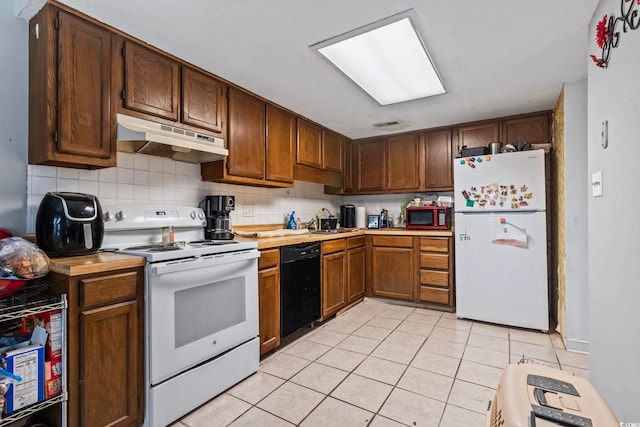 kitchen featuring backsplash, white appliances, light countertops, under cabinet range hood, and light tile patterned floors