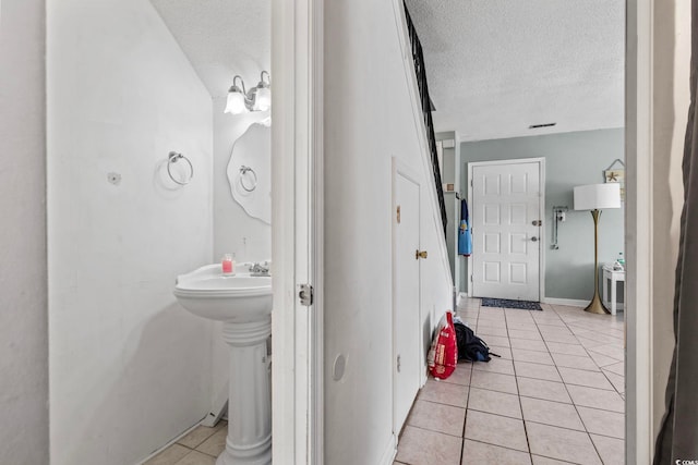 bathroom featuring a textured ceiling, tile patterned floors, and baseboards