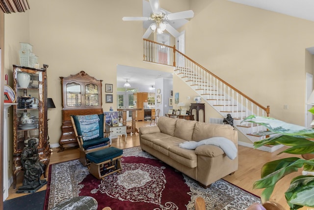 living room with high vaulted ceiling, a ceiling fan, wood finished floors, stairs, and visible vents