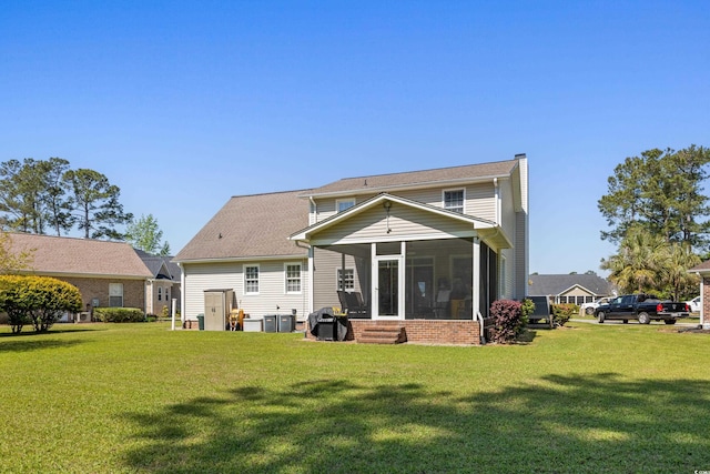 back of property with a sunroom, a chimney, central AC unit, and a lawn