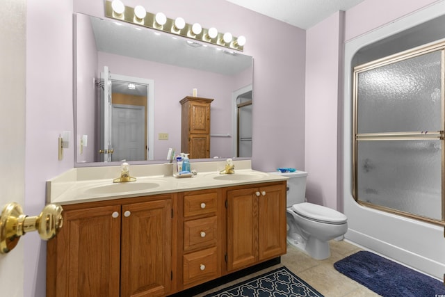 bathroom featuring shower / bath combination with glass door, a sink, double vanity, and toilet