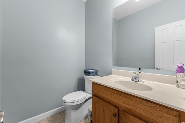 half bathroom with toilet, vanity, and baseboards