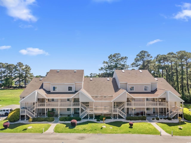 back of property featuring stairway, a lawn, and a balcony