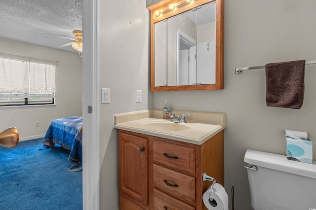bathroom with a textured ceiling, toilet, baseboards, ceiling fan, and vanity
