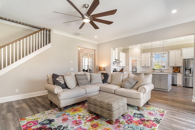 living area featuring baseboards, ornamental molding, dark wood finished floors, and ceiling fan