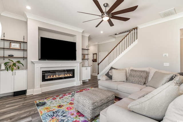 living room with ceiling fan, wood finished floors, stairway, a glass covered fireplace, and ornamental molding