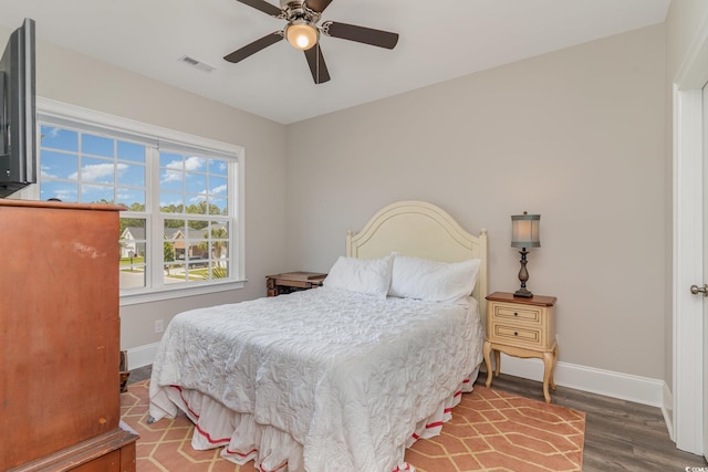 bedroom with baseboards, ceiling fan, wood finished floors, and visible vents