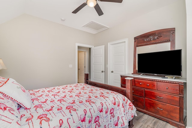 bedroom with ceiling fan, attic access, wood finished floors, and lofted ceiling
