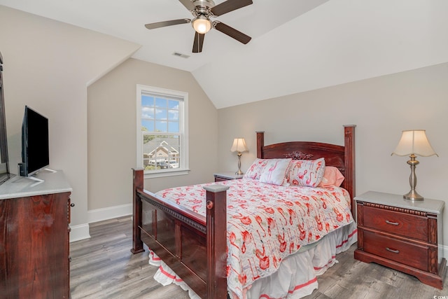 bedroom with baseboards, ceiling fan, wood finished floors, and lofted ceiling