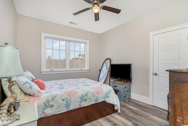 bedroom featuring baseboards, ceiling fan, wood finished floors, and visible vents