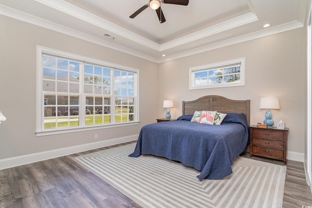 bedroom featuring visible vents, a raised ceiling, baseboards, and wood finished floors