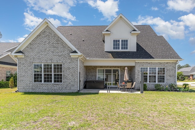 rear view of property featuring brick siding, a hot tub, a patio area, and a yard