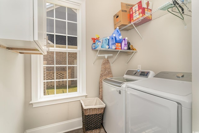 washroom with cabinet space, baseboards, and washing machine and dryer