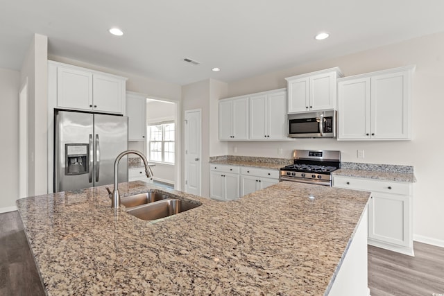 512 Charlton Blvd, Georgetown, SC 29440 - kitchen featuring appliances with stainless steel finishes, a sink, light wood finished floors, white cabinetry, and a kitchen island with sink