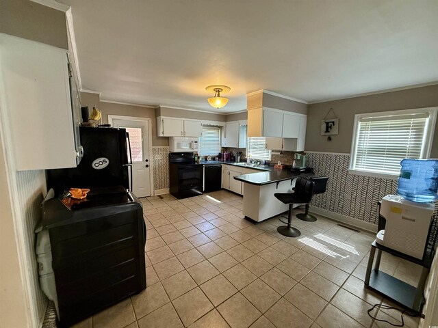 kitchen featuring black appliances, a peninsula, ornamental molding, light tile patterned flooring, and a breakfast bar area