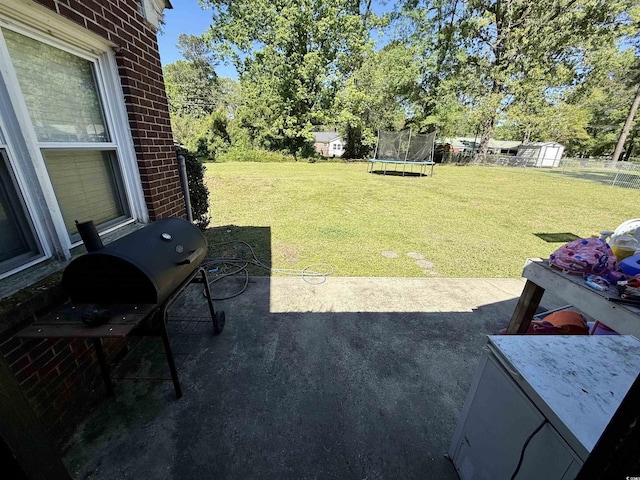 view of grassy yard with a trampoline, a patio, a storage shed, and an outbuilding