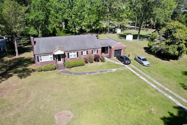 view of front of home featuring an attached garage, driveway, brick siding, a front lawn, and a chimney