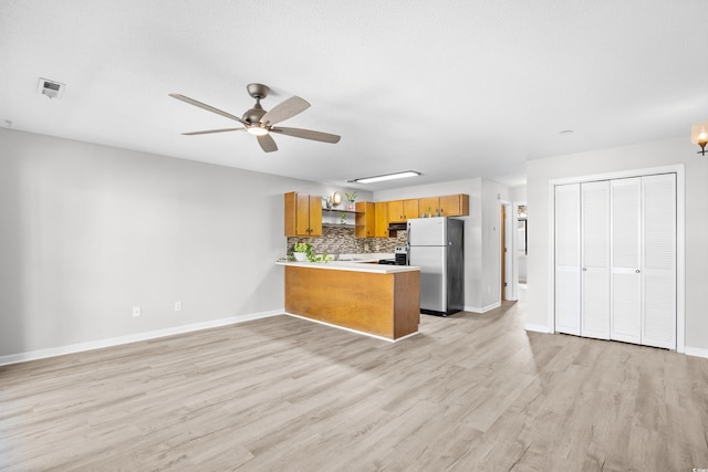 3700 Golf Colony Ln Unit 18-G, Little River, SC 29566 - kitchen with freestanding refrigerator, a peninsula, brown cabinets, and baseboards
