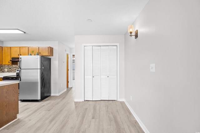 3700 Golf Colony Ln Unit 18-G, Little River, SC 29566 - kitchen featuring appliances with stainless steel finishes, light wood-style flooring, under cabinet range hood, and baseboards