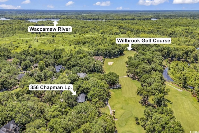 aerial view of a heavily wooded area, a golf club, and a large body of water