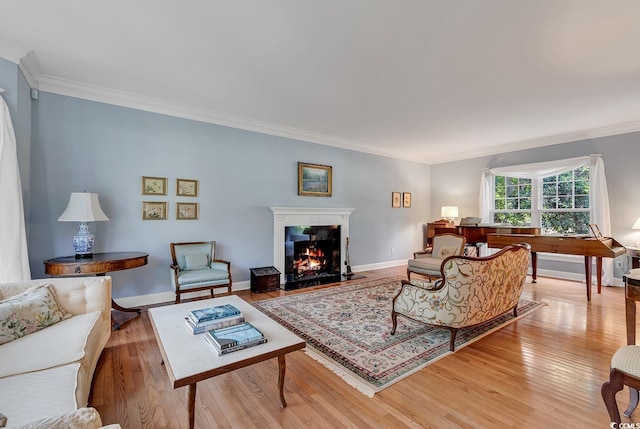 living area with light wood finished floors, crown molding, a high end fireplace, and baseboards