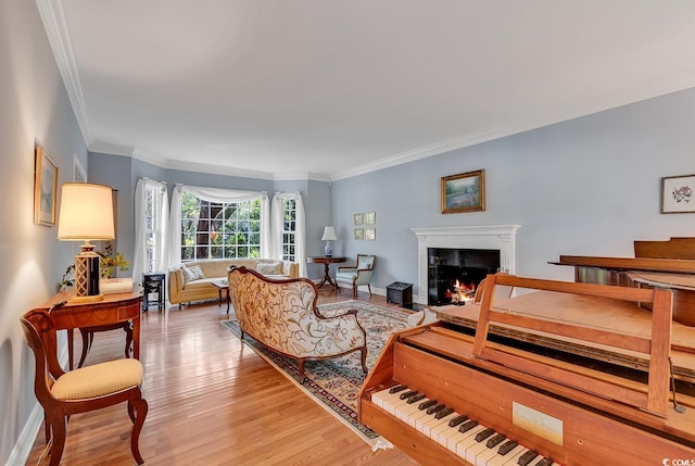living area with ornamental molding, a warm lit fireplace, light wood finished floors, and baseboards