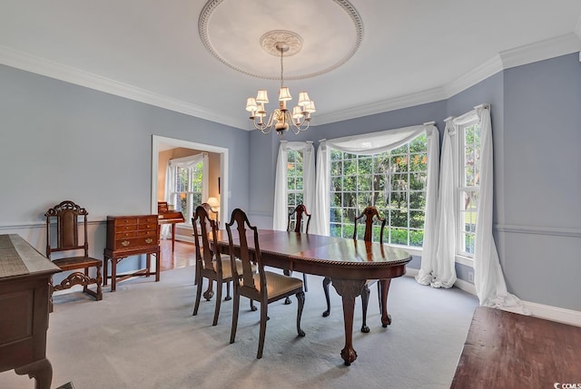 carpeted dining area with a chandelier, crown molding, and baseboards