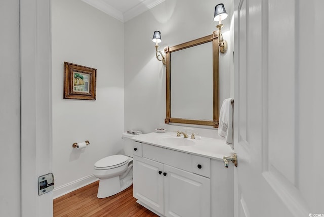 half bathroom with ornamental molding, vanity, wood finished floors, toilet, and baseboards