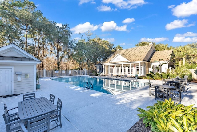 community pool featuring fence, a patio, and outdoor dining area
