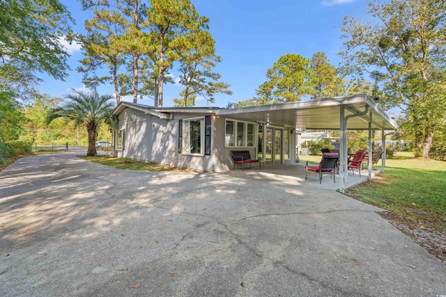 back of property with driveway, a patio, and an attached carport