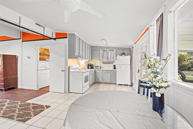 kitchen with white appliances, washer / dryer, light tile patterned floors, exhaust hood, and gray cabinetry