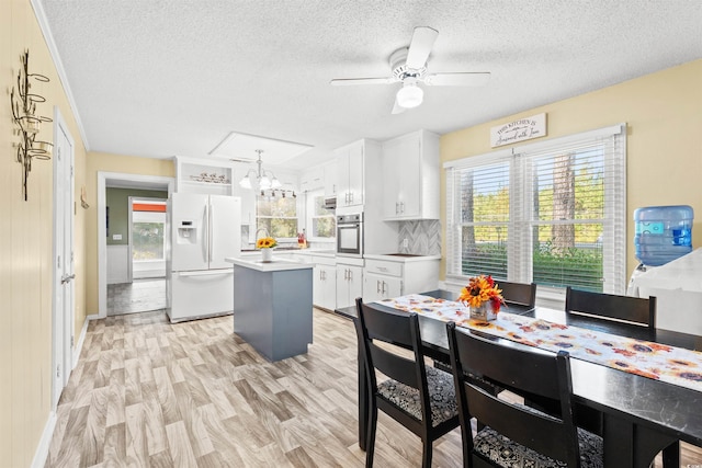 kitchen with white fridge with ice dispenser, white cabinets, a chandelier, plenty of natural light, and a textured ceiling