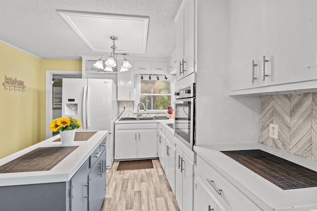 kitchen with a sink, a textured ceiling, white cabinetry, decorative backsplash, and a chandelier
