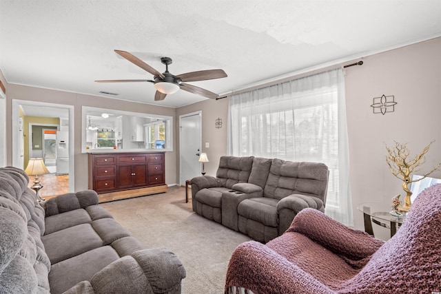 living room featuring a ceiling fan, light carpet, and crown molding